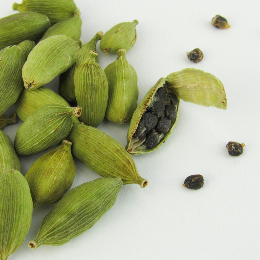 A pile of whole green cardamom pods, one split open